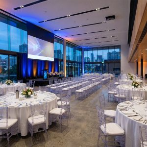 Corporate event setup in a modern Australian function venue with round tables and professional stage lighting